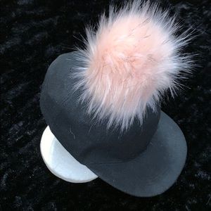 A black cap/ hat with a baby pink puff on the top